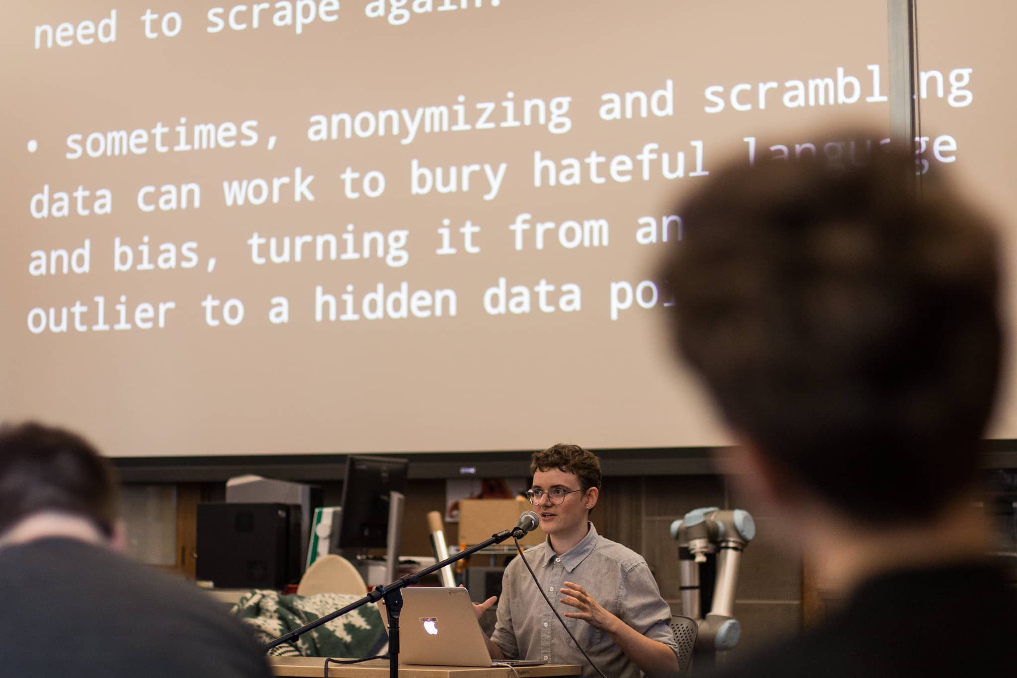 Participant speaks at a podium in front of projected text about the problem with anonymyzing data"